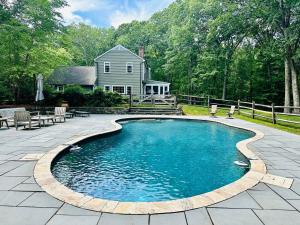 a swimming pool on a patio with a house in the background at Upmarket Country Retreat, Washington, Connecticut in Washington