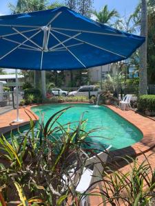 a blue umbrella sitting next to a swimming pool at Beachfront at Silver Sands Hervey Bay in Hervey Bay