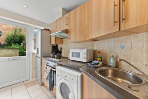 a kitchen with a sink and a washing machine at The Stylish Cottage of Oxford - Sleeps 5 in Oxford
