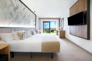 a bedroom with a large white bed and a flat screen tv at Bull Vital Suites & Spa Boutique Hotel - Only Adults in Playa del Ingles