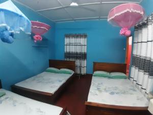 2 camas en una habitación con paredes azules en Amila Guest, en Trincomalee