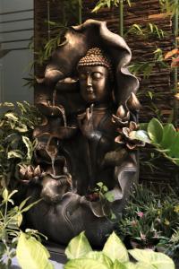 a bronze statue of a buddha in a garden at Hotel Serene Viman Nagar in Pune