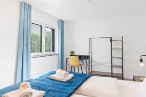ein Schlafzimmer mit einem Bett und einem Schreibtisch mit Handtüchern in der Unterkunft FiNEST Design Stuttgart Airport Messe in Ostfildern