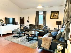 uma sala de estar com um sofá de couro e mesas em Langahlíð Guesthouse - Privatete Forest - em Hella