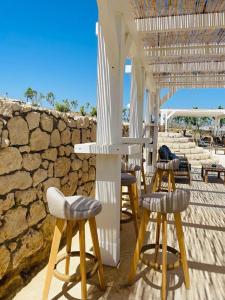 a group of stools sitting next to a stone wall at LASSION GOLDEN BAY Sea view in Sitia