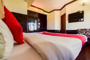 a bedroom with a bed with red and white pillows at Hotel Shubham in Shimla