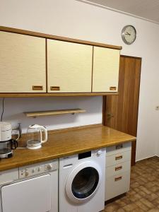 cocina con lavadora y reloj en la pared en Ferienhaus Heiderose, en Schneverdingen