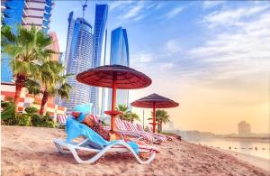 Corniche AD - Stunning Room في أبوظبي: مجموعة من الكراسي والمظلات على الشاطئ