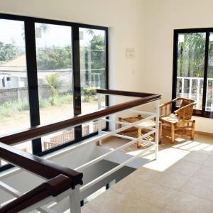 Zimmer mit großen Fenstern, einem Tisch und einem Stuhl in der Unterkunft Residencial Aeroporto in São Tomé