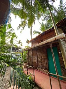 uma casa com uma porta verde e palmeiras em Hobknob, Goa - hostel with a pool em Nogorcem