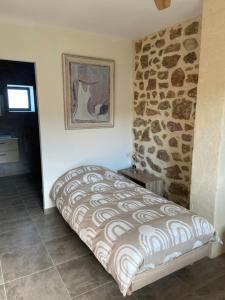 uma cama num quarto com uma parede de pedra em Mas Bô Regard em Aiguèze