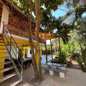 uma casa com uma varanda com uma mesa e um balanço em Hobknob, Goa - hostel with a pool em Nogorcem