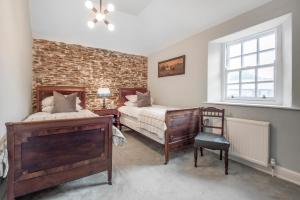 1 Schlafzimmer mit 2 Betten, einem Stuhl und einem Fenster in der Unterkunft Emmetts Grange House in Minehead