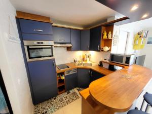 eine Küche mit blauen Schränken und einem Holztisch in der Unterkunft Appartement Les Sables-d'Olonne, 3 pièces, 4 personnes - FR-1-92-876 in Les Sables-dʼOlonne