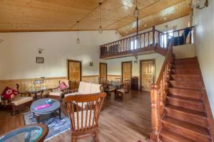 a living room with a staircase and tables and chairs at ROSASTAYS Mukteshwar Rosa Parvada in Mukteswar
