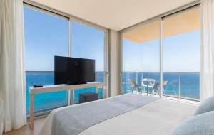a bedroom with a bed with a tv and large windows at Hotel Palia Maria Eugenia in Calas de Mallorca