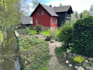 une maison rouge avec une rivière devant elle dans l'établissement Ferienwohnungen im Landhaus, à Burg
