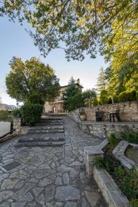 une passerelle en pierre avec bancs et arbres dans un parc dans l'établissement Archontiko Fiamegou Hotel&Spa, à Synikia Mesi Trikalon