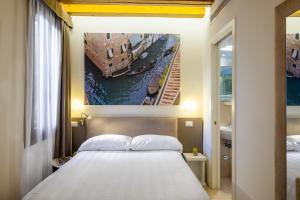 1 dormitorio con 1 cama y una pintura de un canal en Leone Hotel en Venecia