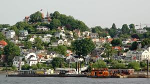uma cidade numa colina com casas e um barco em Peaceful Apartment- 3 Zi- Loggia & Garden in Blankenese- em Hamburgo