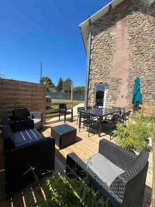 eine Terrasse mit einem Tisch und Stühlen sowie ein Backsteingebäude in der Unterkunft Gîte Le Rucher de Saint Florent - DABNB in Limoges