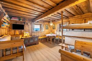 una sala de estar con TV y una cama en una cabaña en Historisches Apartment Duregghof, en San Genesio Atesino