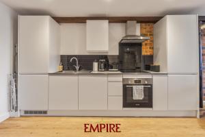 a kitchen with white cabinets and a stove at Stylish 2 Bed Apartment Burton On Trent in Burton upon Trent