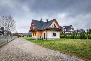 a small house with a black roof in a yard at Magiczny Domek in Białka Tatrzanska