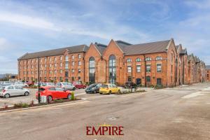 un grand bâtiment en briques avec des voitures garées dans un parking dans l'établissement Stylish 2 Bed Apartment Burton On Trent, à Burton-on-Trent