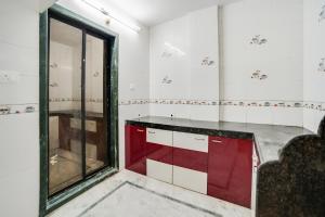 una cocina con armarios rojos y blancos y una ventana en OYO Flagship Galaxy Grand B&B, en Panvel