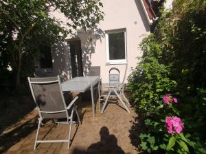 um pátio com uma mesa, cadeiras e flores em Haus am Hafen em Neustadt in Holstein