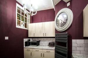 een keuken met paarse muren en een klok aan de muur bij Bridge Street Rows City Centre Apartment by Rework Accommodation in Chester