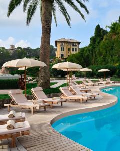a row of lounge chairs and umbrellas next to a swimming pool at Grand Hotel Miramare in Santa Margherita Ligure