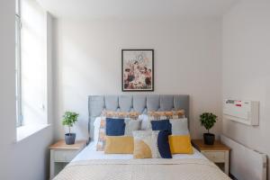 a bedroom with a bed with blue and yellow pillows at Sweet Dreams - Farringdon - by Frankie Says in London