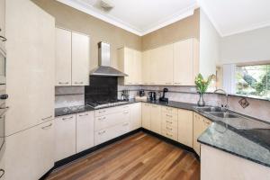 a kitchen with white cabinets and black counter tops at Eastwood Central, Walk to Station & Shops, Drive to Olympic in Sydney
