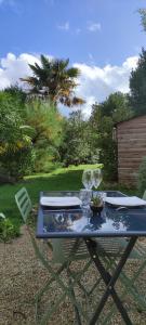 a table in a garden with a glass at La Patte Charentaise Parking gratuit Le calme en ville in Saintes