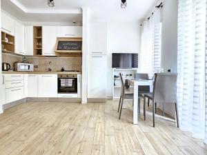 cocina con armarios blancos, mesa y sillas en Maremè Guest House Ostia, en Lido di Ostia