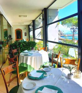 a dining room with two tables and chairs and windows at Hotel La Bussola in Amalfi