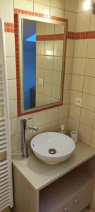 een badkamer met een witte wastafel en een spiegel bij La Patte Charentaise Parking gratuit Le calme en ville in Saintes