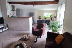 een woonkamer met een bank, stoelen en een tafel bij La Patte Charentaise Parking gratuit Le calme en ville in Saintes