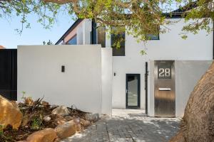 a white building with a door and a tree at Neighbourgood 1st Crescent in Cape Town