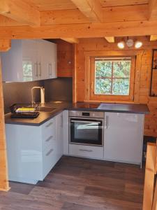 a kitchen with white cabinets and a window in a cabin at Christinas Ferienhäuser in Rodewald in Neudorf Rodewald