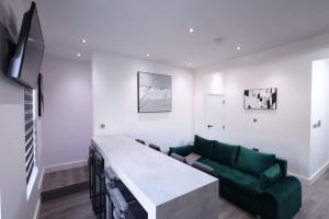 ein Wohnzimmer mit einem grünen Sofa und einem TV in der Unterkunft PrimeLocation! Spacious 4BR Apt Market St Watford! in Watford