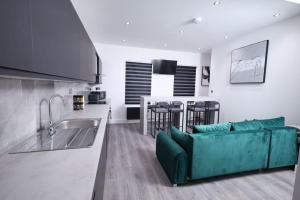 ein Wohnzimmer mit einem grünen Sofa und einer Küche in der Unterkunft PrimeLocation! Spacious 4BR Apt Market St Watford! in Watford