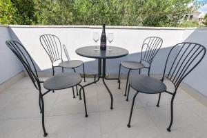 een tafel met vier stoelen en een fles wijn bij Double L House in Novalja