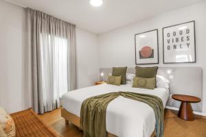 a bedroom with a large white bed with green pillows at Agaete 2BR Coastal Retreat in Agaete