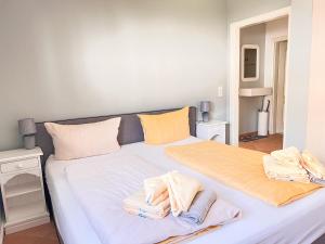 - un grand lit blanc avec des serviettes dans l'établissement Haus Elaine App. 19, à Westerland