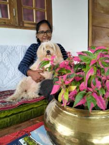 a woman sitting on a couch with a dog at Valley View Homestay in Darjeeling