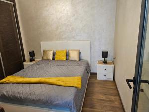 een slaapkamer met een bed met een gele deken bij Belle Apparemment à agadie bay in Agadir