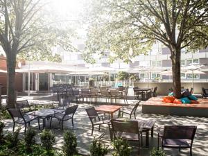 an outdoor patio with tables and chairs and trees at Novotel Toulouse Purpan Aéroport in Toulouse